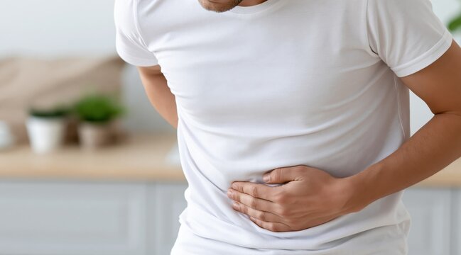 Man in white shirt clutching stomach and back in pain