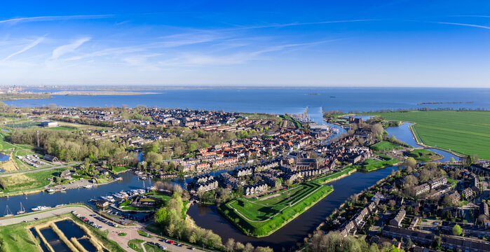 Aerial drone panorama of the historic fortified town of Muiden in the Netherlands with star-shaped bastions, harbor on the Vecht river and the IJmeer lake beyond on a sunny spring day