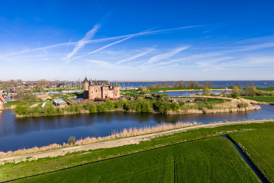 Aerial landscape of Dutch polders and Muiderslot Castle in the distance with the Vecht river, IJmeer lake and historic town of Muiden in the Netherlands