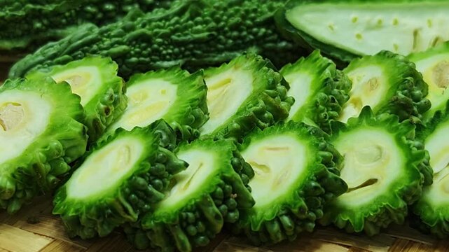 Slice the bitter melon on a wooden cutting board.