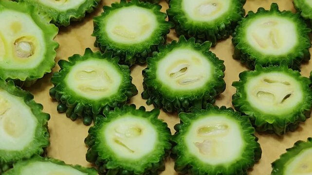 Slice the bitter melon on a wooden cutting board.