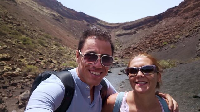 Smiling couple taking a selfie inside the El Cuervo volcano in Lanzarote