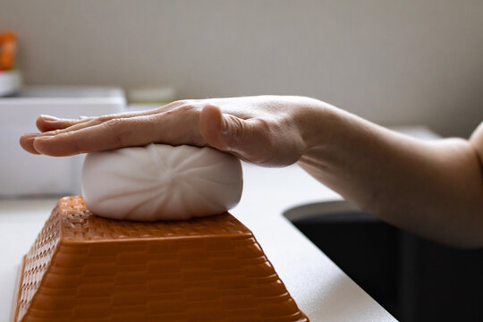 Close up of hand squeezing a soft steamed bun shaped sensory toy. Minimal lifestyle, tactile stimulation and stress management concept.