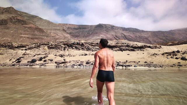 Muscular man walking out of the ocean at Risco beach, Lanzarote