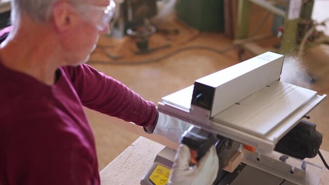 Senior carpenter cutting wood with a miter saw