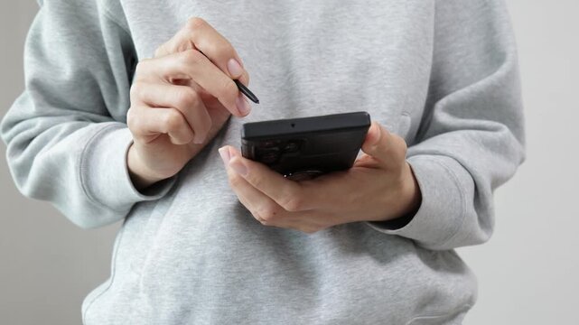 Hands using foldable smartphone and stylus on white background, mobile technology, touchscreen interaction, modern communication device.