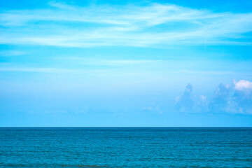 Obraz premium Tropical Nature clear sky and summer sea water under a clear blue sky with beautiful clouds and bright sunlight. Perfect for summer vacation and travel background