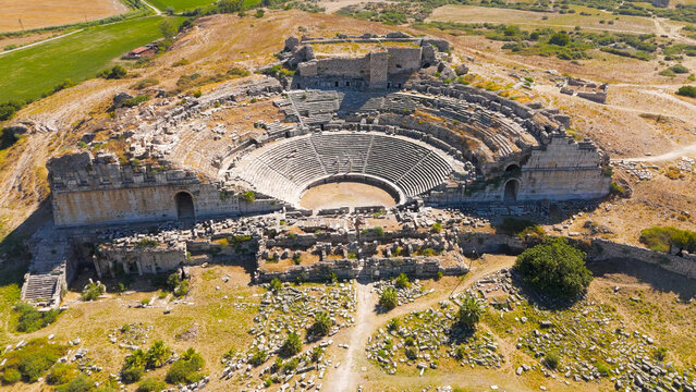 Balat, Turkey. Aerial drone approach to ancient Theatre of Miletus filling the frame with view of green fields. Aerial View