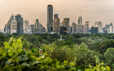 Fototapeta premium Panoramic cityscape of Bangkok business district overlooking Lumphini Park during golden hour.