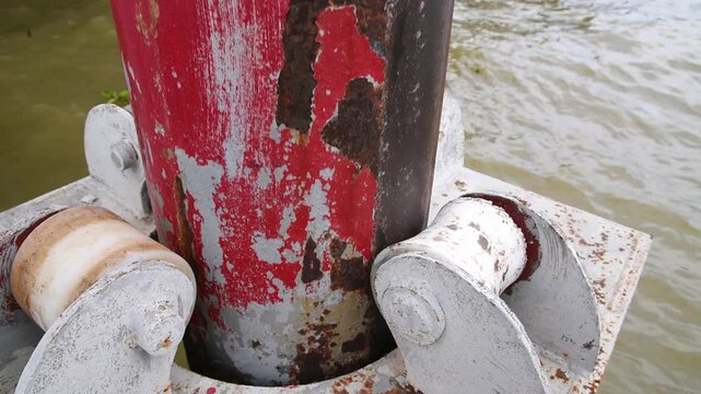 rusty floating dock guide pile with rollers moving along river waves level, weathered red metal pier guide pile with roller system for floating pontoon