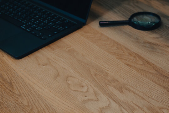 Black Laptop and Magnifying Glass on Wooden Desk, Research and Investigation Business Concept with Copy Space