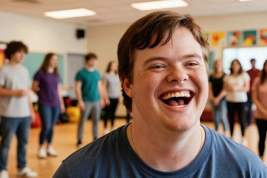 Young man with Down syndrome laughs during an improv class. Diverse students participate in fun theatre arts workshop. Group learns creativity together in positive inclusive setting.