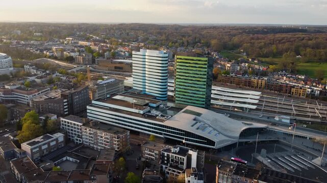 Arnhem Centraal Station in Arnhem Centrum Gelderland Netherlands at Stationsplein with Park Tower and Rijntoren showing railway interchange bus terminal and rail corridors drone lateral orbit right