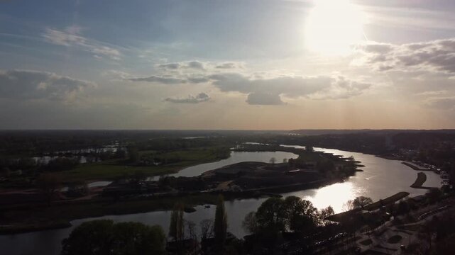 Nederrijn river in Arnhem Gelderland Netherlands within Rhine Meuse delta system with levees floodplain and embankment roads showing hydraulic engineering and water management drone rising and pan