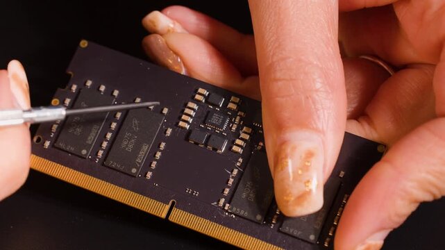 Macro shot of technician using precision tool on ram memory module circuit board.