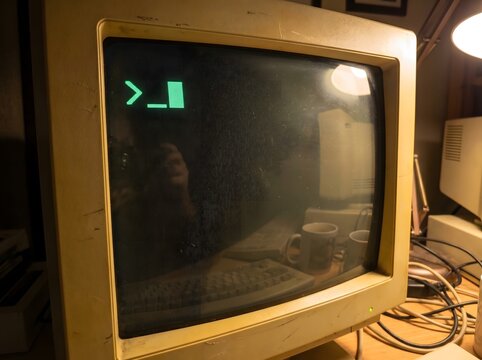Close-up of an old-fashioned computer monitor displaying a command-line interface with a blinking cursor, evoking a sense of retro technology and early computing