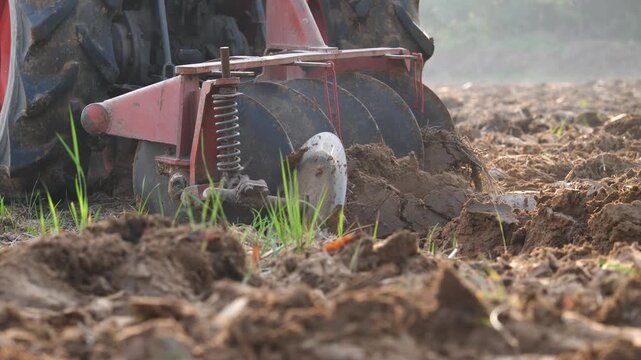 A tractor is working in a rice field, preparing the soil before planting rice. (Concept)