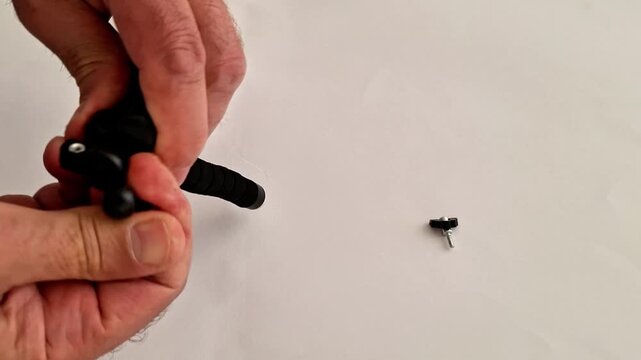 Hands holding a compact black tripod with segmented adjustable legs and mounting screw on a white surface, highlighting portable gear for photography and videography setups