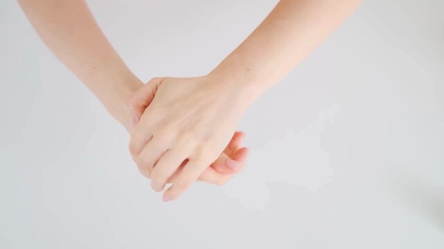 Close-up of two hands gently holding each other in a gesture of support and connection.
