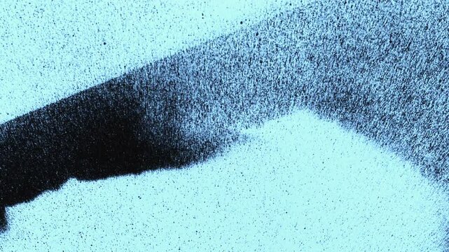 Spray paint mist in slow motion. Aerosol particles floating against a dark black background.