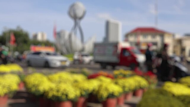 Bokeh view of yellow chrysanthemum pots for sale on a Vietnamese street for Tet holiday in Vietnam. Potted flowers at a local market with Nha Trang city traffic. Blurred background footage.