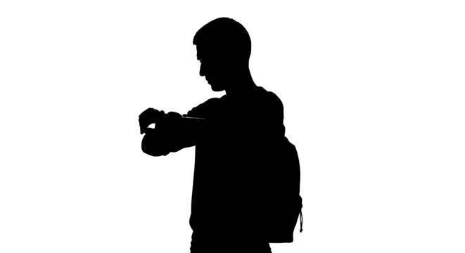 Silhouette of a young man checking his watch with a backpack against a white background checking time management