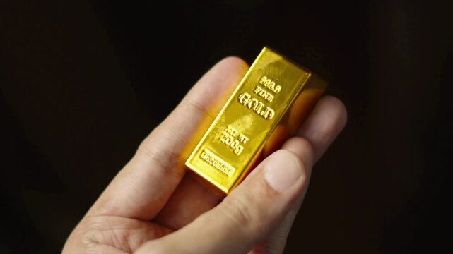 Close-up of a Hand Holding a Gold Bar.