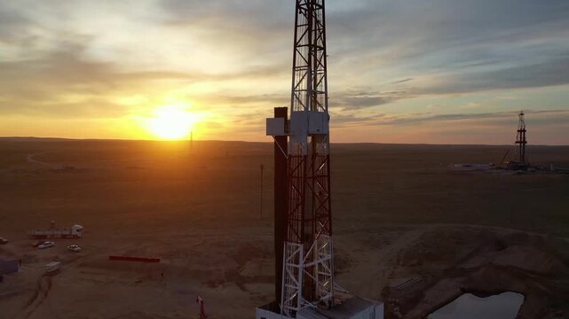 Close view of drilling rig at sunset in active gas field.