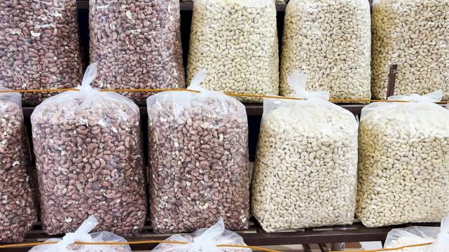 rows of raw and roasted cashew nuts in transparent bags at retail shop at goa
