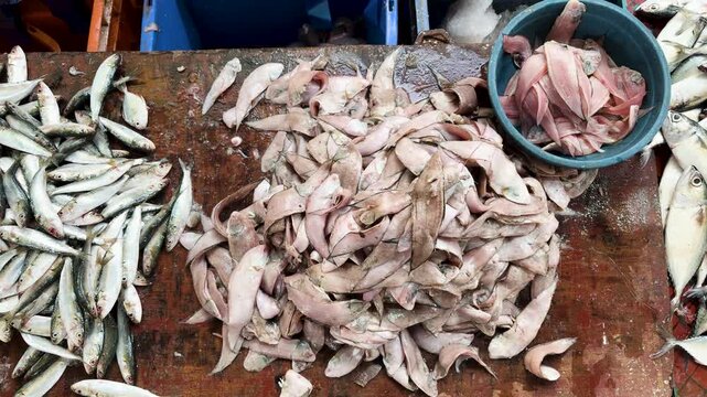 assorted fresh fish pieces and small fish on wooden table in seafood market for retail sale