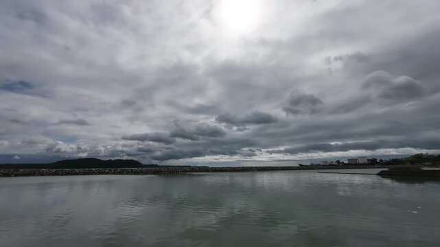 Timelapse of clouds moving over the ocean iloilo city with Guimaras Island in the background, Philippines. Static camera captures tropical seascape horizon motion and calm water on a cloudy day