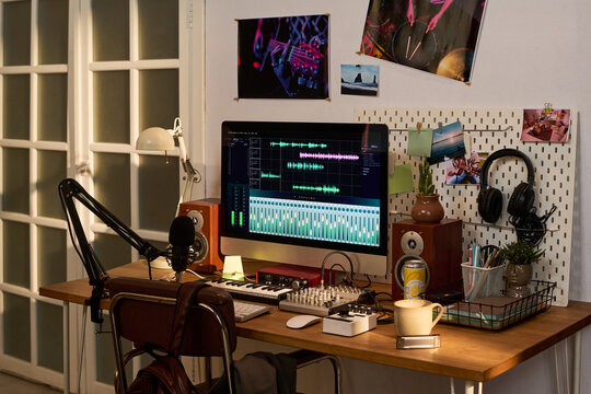 Home podcast studio featuring computer editing audio, microphone recording setup, headphones, mixer, speakers. Ideal for content creation, remote broadcasting, audio production marketing