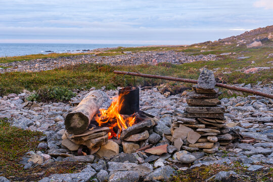 Cooking dinner in a pot over a campfire on the shore of the Barents Sea. Kola Peninsula, Russia.