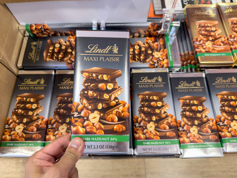 LANGKAWI, MALAYSIA - MAR 18, 2026: Close up of a person holding Lindt Maxi Plaisir dark hazelnut chocolate bar in a retail store.