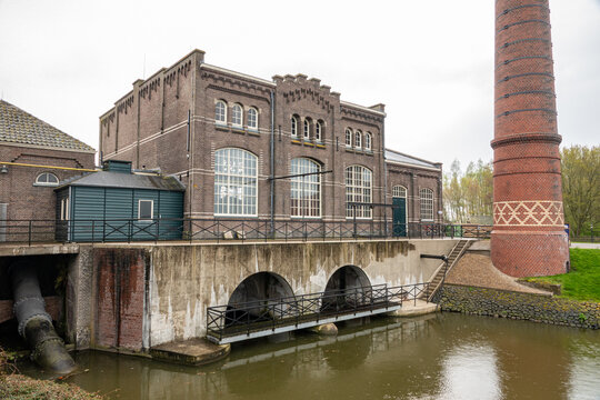 View of the Dutch Steam Engine Museum with its historic brick facade and tall chimney by the water in Medemblik, Noord-Holland, Netherlands.