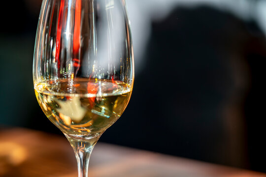 Close-up of a white wine glass with colourful reflections and soft bokeh background in a cosy restaurant setting. Ideal for hospitality, luxury dining, and lifestyle themes.