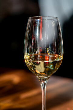 Close-up of a white wine glass with colourful reflections and soft bokeh background in a cosy restaurant setting. Ideal for hospitality, luxury dining, and lifestyle themes.