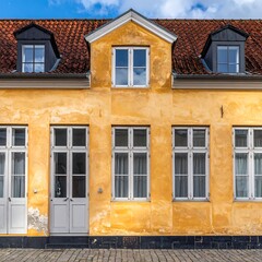 Obraz premium Historical building with yellow facade and red tiled roof under blue sky