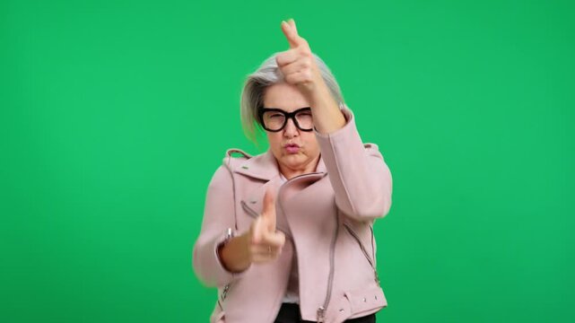 Stylish senior woman making a gun gesture on a green screen