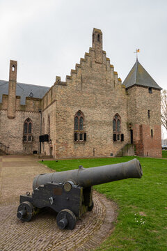 View of Radboud Castle with a historic iron cannon on a carriage in the foreground, brick walls, and stepped gables Medemblik, Noord-Holland, Netherlands.