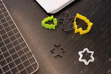 Cookie cutters sitting on dark kitchen counter with green  and  yellow trees, gingerbread, cooling r © wavebreak3