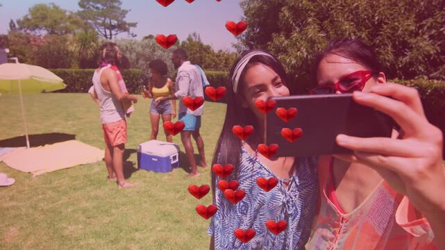 Creators raising phone for selfie on yard, AR hearts floating over frame friends handling cooler