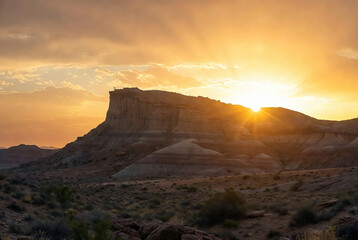 Obraz premium A dramatic sunset over sandstone cliffs in a desert landscape.