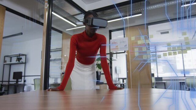 VR headset activating, woman tech professional leaning at table navigating code grids for design
