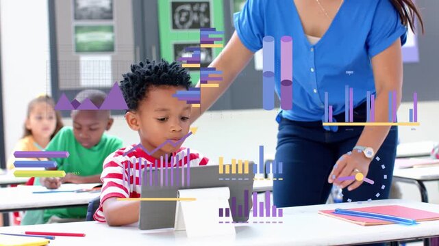 Female teacher approaching boy at desk, pointing tablet, guiding education with charts floating