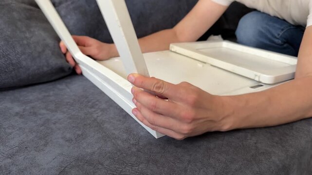 man assembling small table or stool frame at home, furniture setup process, home improvement, DIY activity, domestic routine