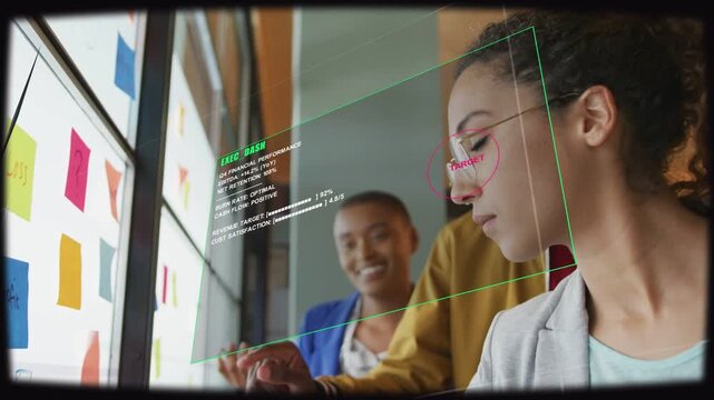 Right woman leaning, colleague pointing and AR overlay appearing, editing sticky notes for business