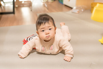 Naklejka premium うつ伏せでカメラを見つめるうさぎ柄ロンパースの日本人の男の赤ちゃん