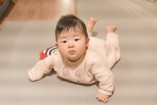 うつ伏せでカメラを見つめるうさぎ柄ロンパースの日本人の男の赤ちゃん