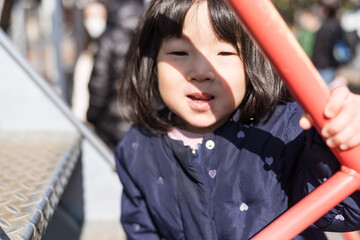 Obraz premium 公園の滑り台を滑り降りる日本人の女の子の幼児